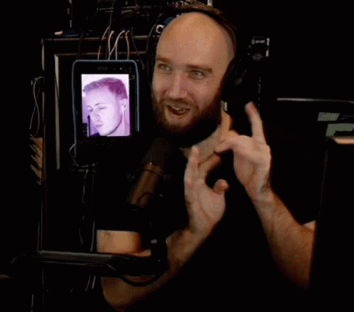A Man Wearing Headphones With A Picture Of A Man On A Tablet In Front Of Him GIF