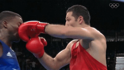 A Man Wearing Red Boxing Gloves Punches Another Man In A Blue Tank Top GIF