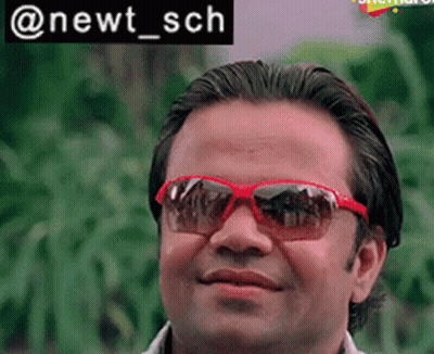A Man Wearing Red Sunglasses Is Smiling In Front Of A Sign That Says Newt Sch GIF