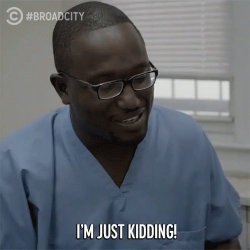 A Man Wearing Scrubs And Glasses Is Saying I 'M Just Kidding GIF
