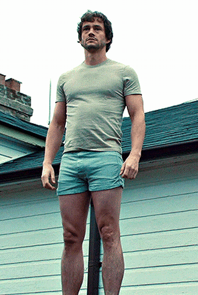 A Man Wearing Shorts And A T-Shirt Is Standing On A Pole GIF