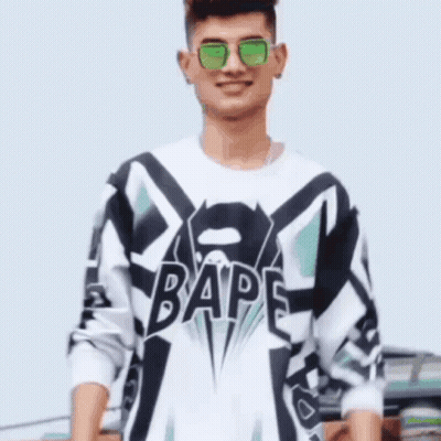 A Man Wearing Sunglasses And A Bape Shirt Is Smiling . GIF