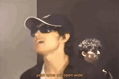 A Man Wearing Sunglasses And A Baseball Cap Is Talking . GIF