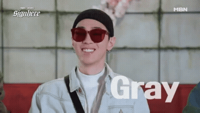 A Man Wearing Sunglasses And A Beanie Is Smiling While Sitting On A Red Couch . GIF