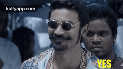 A Man Wearing Sunglasses And A Beard Is Smiling While Standing Next To Another Man . GIF