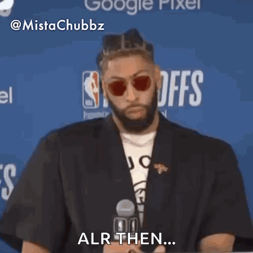 A Man Wearing Sunglasses And A Black Jacket Is Sitting In Front Of A Microphone And Says Alr Then . GIF