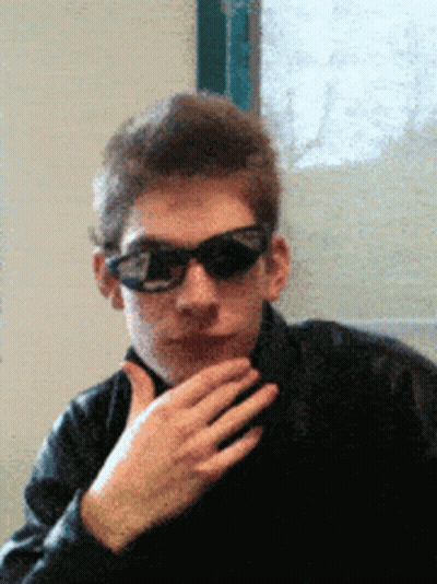 A Man Wearing Sunglasses And A Black Jacket Looks At The Camera GIF