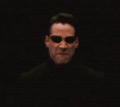 A Man Wearing Sunglasses And A Black Shirt Is Looking At The Camera GIF