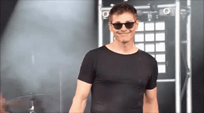 A Man Wearing Sunglasses And A Black T-Shirt Is Smiling GIF