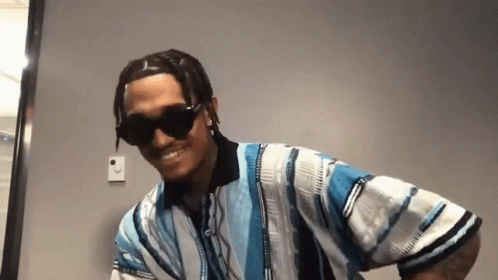 A Man Wearing Sunglasses And A Blue And White Striped Shirt Is Smiling . GIF