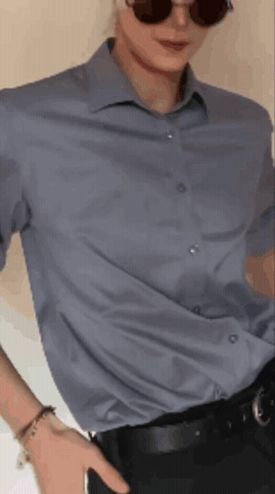 a man wearing sunglasses and a blue shirt holds his hand in his pocket
