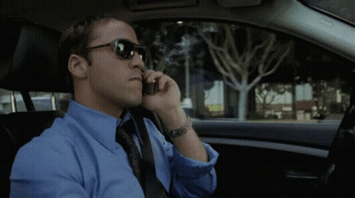 A Man Wearing Sunglasses And A Blue Shirt Is Talking On A Cell Phone GIF