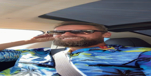 A Man Wearing Sunglasses And A Blue Shirt With Palm Trees Is Smiling GIF
