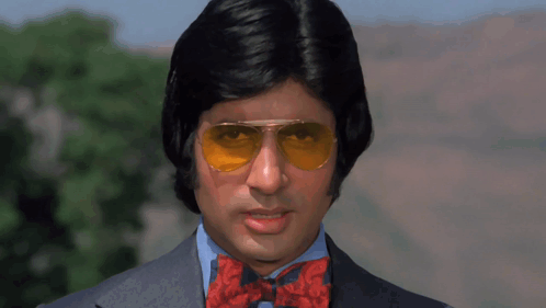 A Man Wearing Sunglasses And A Bow Tie Is Looking At The Camera GIF