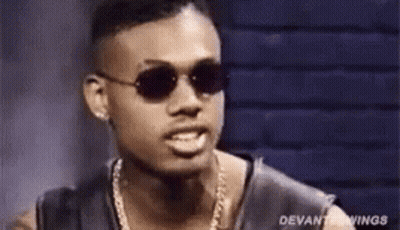 A Man Wearing Sunglasses And A Chain Around His Neck Is Making A Funny Face . GIF