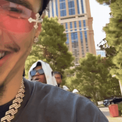 A Man Wearing Sunglasses And A Chain Around His Neck Smiles For The Camera GIF