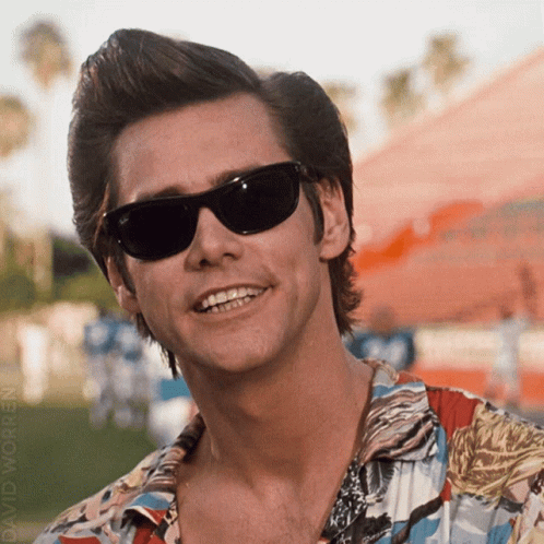 A Man Wearing Sunglasses And A Colorful Shirt Smiles GIF