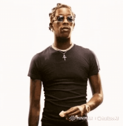 A Man Wearing Sunglasses And A Cross Necklace Is Standing In Front Of A White Background GIF