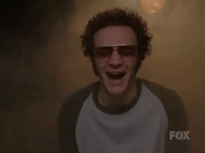A Man Wearing Sunglasses And A Fox Shirt Is Screaming In A Dark Room . GIF