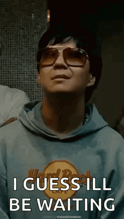 A Man Wearing Sunglasses And A Hard Rock Cafe Hoodie Is Waiting . GIF