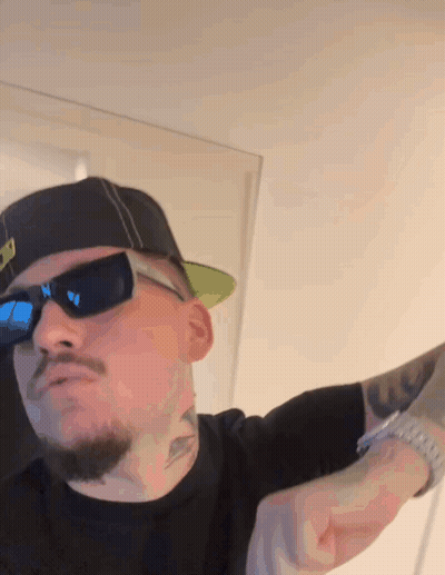 A Man Wearing Sunglasses And A Hat Has A Tattoo On His Arm That Says U. GIF