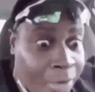 A Man Wearing Sunglasses And A Hat Is Making A Funny Face In A Car . GIF