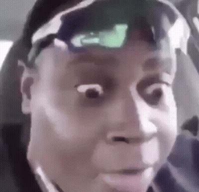 A Man Wearing Sunglasses And A Hat Is Making A Funny Face While Sitting In A Car . GIF