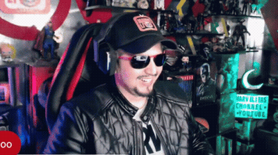 A Man Wearing Sunglasses And A Hat Is Smiling In Front Of A Sign That Says Marvelitas Channel GIF