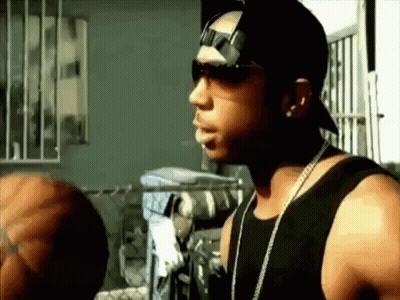 A Man Wearing Sunglasses And A Hat Is Standing In Front Of A Window GIF