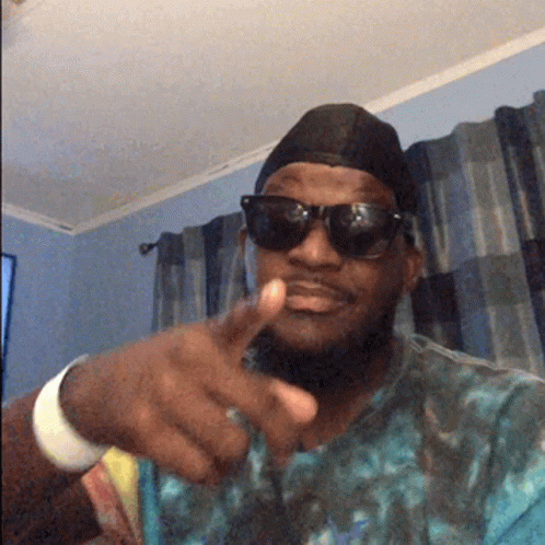 A Man Wearing Sunglasses And A Hat Points His Finger GIF