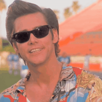 A Man Wearing Sunglasses And A Hawaiian Shirt Smiles GIF