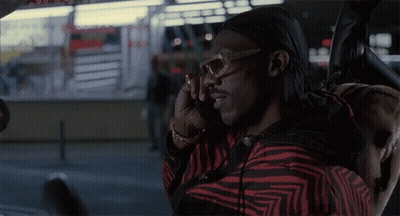A Man Wearing Sunglasses And A Head Scarf Talks On A Cell Phone GIF