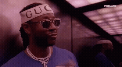 A Man Wearing Sunglasses And A Headband With The Word Guc On It Is Standing In An Elevator . GIF