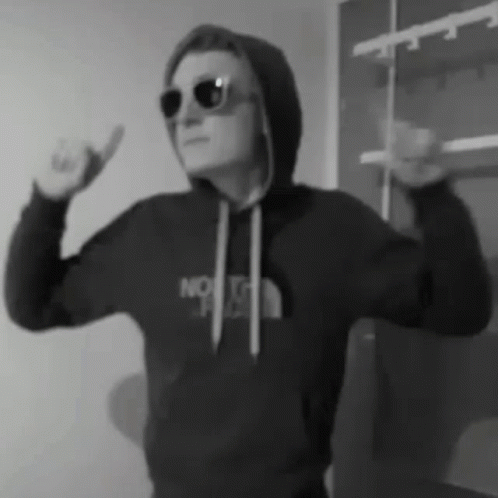 A Man Wearing Sunglasses And A Hoodie Is Making A Funny Face . GIF