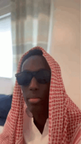 A Man Wearing Sunglasses And A Keffiyeh Is Making A Funny Face . GIF
