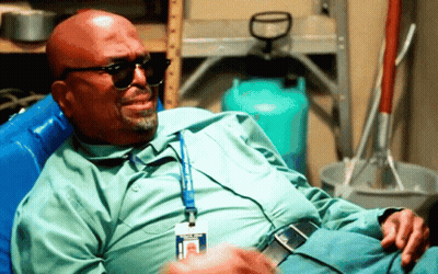 A Man Wearing Sunglasses And A Name Tag With The Letter H On It Is Sitting In A Chair GIF