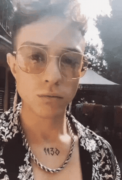 A Man Wearing Sunglasses And A Necklace Has A Tattoo On His Chest That Reads 1130 GIF