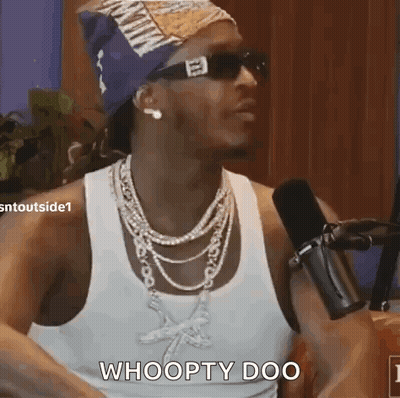 A Man Wearing Sunglasses And A Necklace Is Sitting In Front Of A Microphone And Says Whoopty Doo . GIF