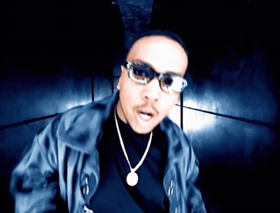 A Man Wearing Sunglasses And A Necklace With A Pendant GIF