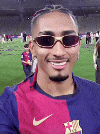 A Man Wearing Sunglasses And A Nike Shirt Is Smiling GIF