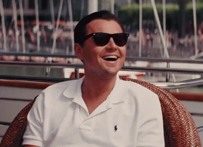 A Man Wearing Sunglasses And A Polo Shirt Smiles GIF