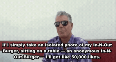A Man Wearing Sunglasses And A Purple Shirt Is Sitting On A Table And Talking About A Burger GIF