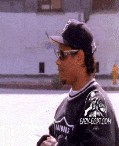 A Man Wearing Sunglasses And A Raiders Jersey Is Walking Down The Street GIF