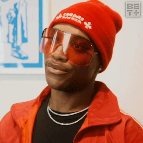 A Man Wearing Sunglasses And A Red Beanie With Chrome Hearts On It GIF