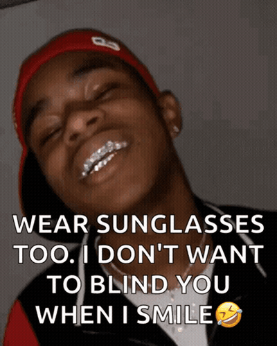A Man Wearing Sunglasses And A Red Hat Is Smiling GIF