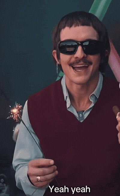 A Man Wearing Sunglasses And A Red Vest Is Holding A Sparkler And Saying Yeah Yeah GIF