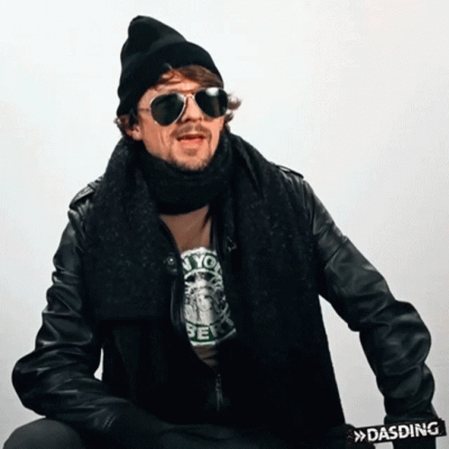A Man Wearing Sunglasses And A Scarf Has A Dasding Belt Around His Waist GIF