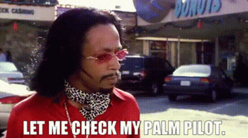 A Man Wearing Sunglasses And A Scarf Is Standing On A Street . GIF