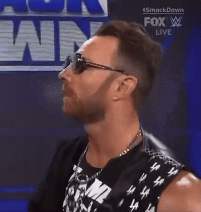 A Man Wearing Sunglasses And A Sleeveless Shirt Is Standing In Front Of A Fox Live Sign . GIF