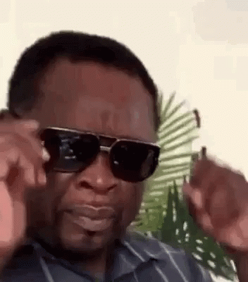 A Man Wearing Sunglasses And A Striped Shirt Is Making A Face . GIF